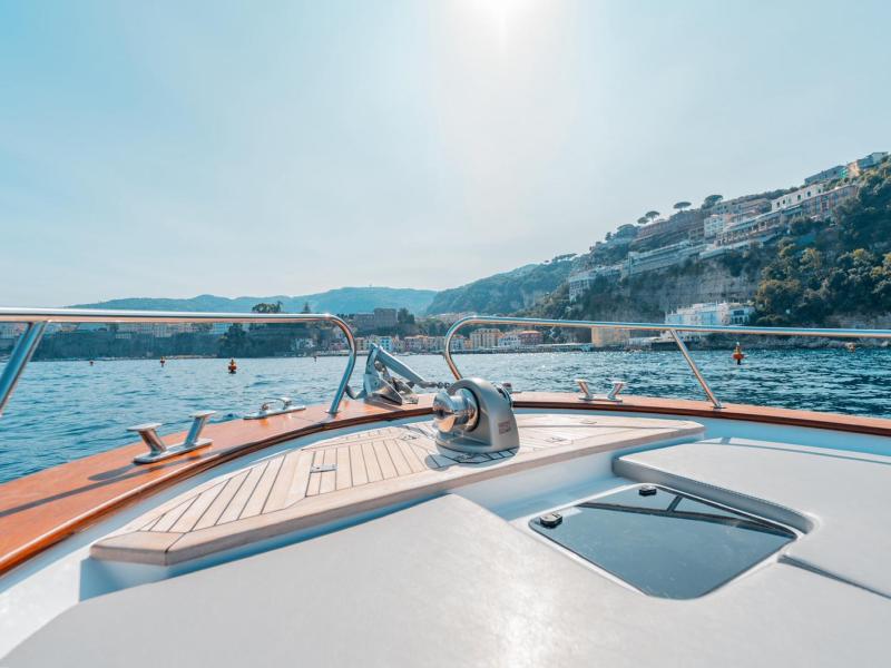 View from a boat deck facing a coastal town with hills and clear sky.