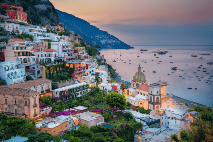 Scenic view of Positano with colorful buildings and boats at sunset on the Amalfi Coast.