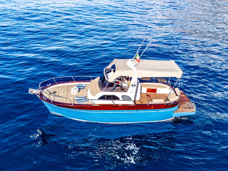 A small blue and white boat with canopy on calm blue water.