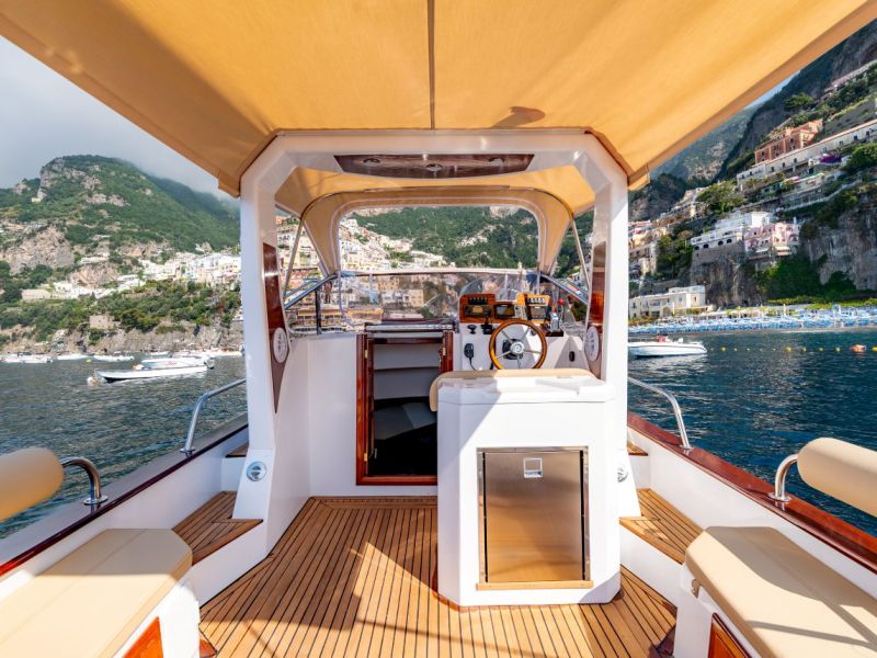 View from a boat's deck towards a coastal town with cliffs and buildings.