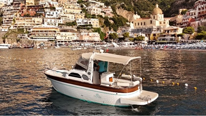 Boat in coastal waters with a town and hills in the background.